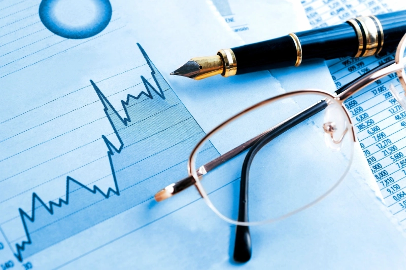 A pen, glasses and some papers on top of a table.